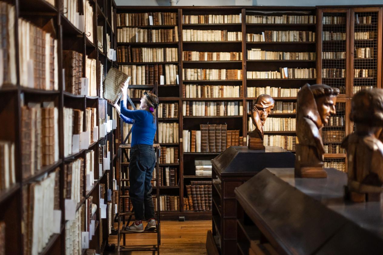 Een medewerkster verzamelt in de oude bibliotheek boeken die naar Google Books verzonden kunnen worden