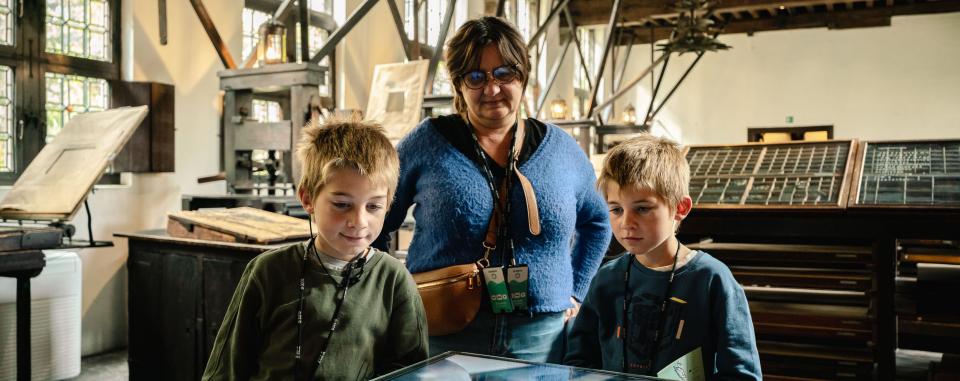 Twee kinderen met een ouder in de drukkerij