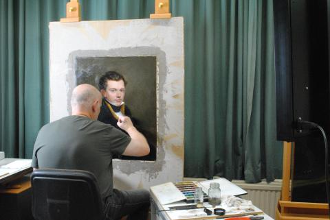 Een man restaureert een portret van een jongeman