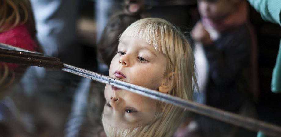 meisje kijkt in toonkast, dat lukt - door haar grootte - net