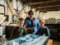 Twee kinderen met een ouder in de drukkerij